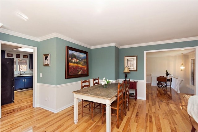 dining room with ornamental molding and light wood-type flooring