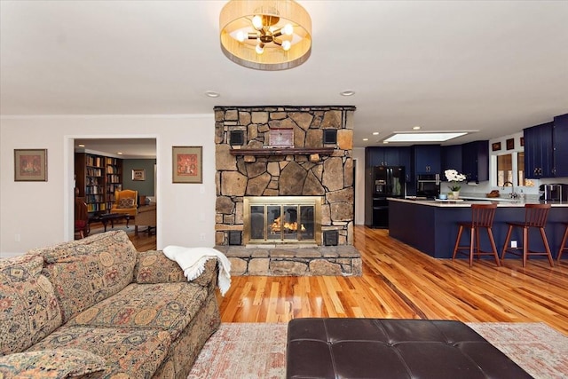living room with light wood-style floors, a notable chandelier, and a fireplace
