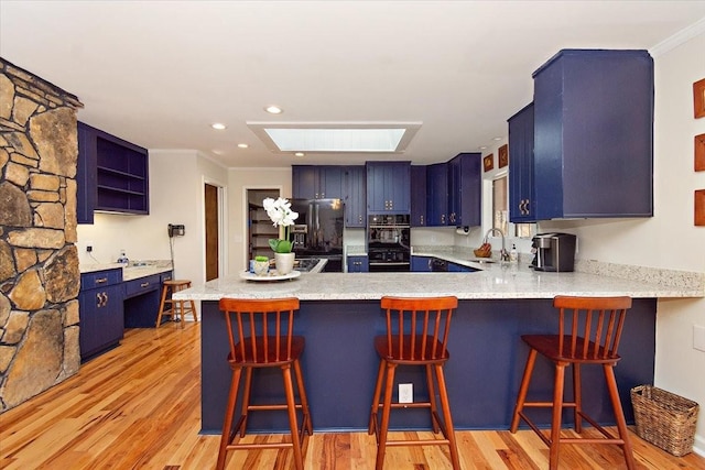 kitchen with open shelves, black fridge, a sink, blue cabinetry, and a peninsula