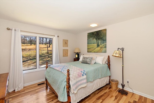 bedroom featuring baseboards, wood finished floors, and visible vents