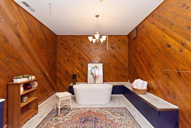 full bath featuring an inviting chandelier, a soaking tub, wood walls, and visible vents