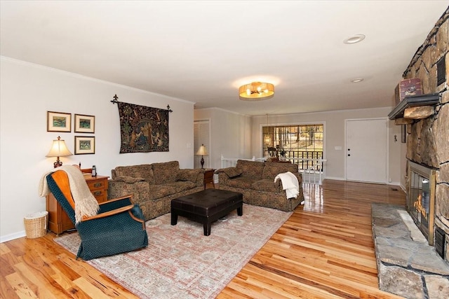 living room with ornamental molding, a fireplace, baseboards, and wood finished floors