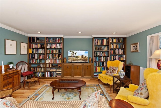 living area featuring built in features, ornamental molding, bookshelves, and wood finished floors