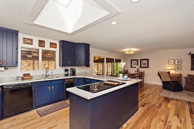 kitchen featuring a sink, light countertops, blue cabinetry, a peninsula, and black appliances