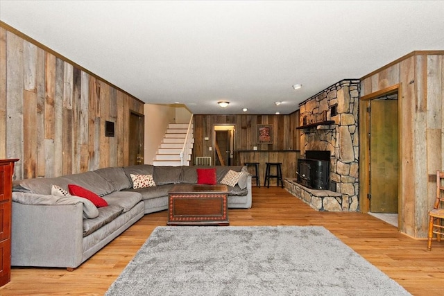 living room featuring visible vents, wood walls, stairs, and light wood-style flooring