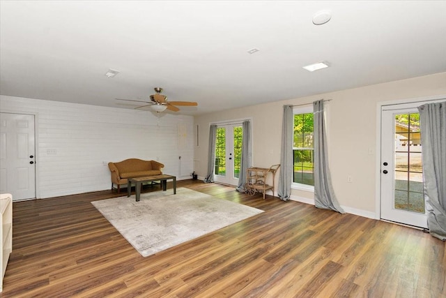 living area with baseboards, ceiling fan, french doors, and wood finished floors