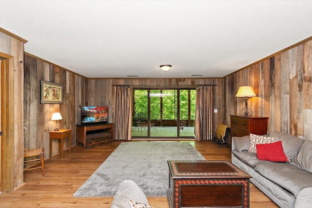living area featuring wooden walls, ornamental molding, and light wood-style floors