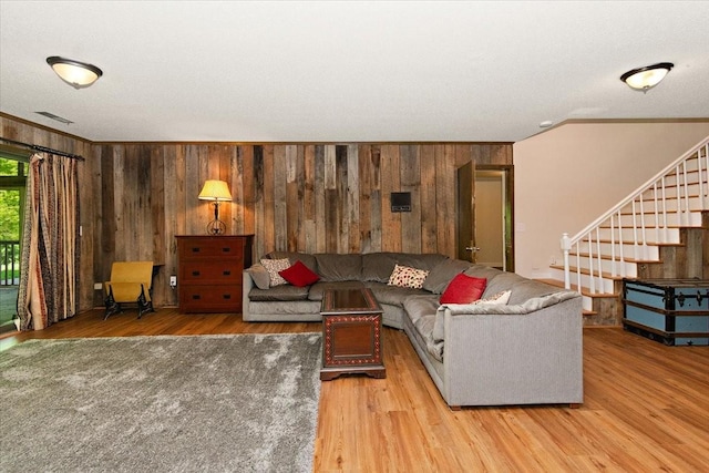 living room featuring ornamental molding, wood walls, wood finished floors, and visible vents