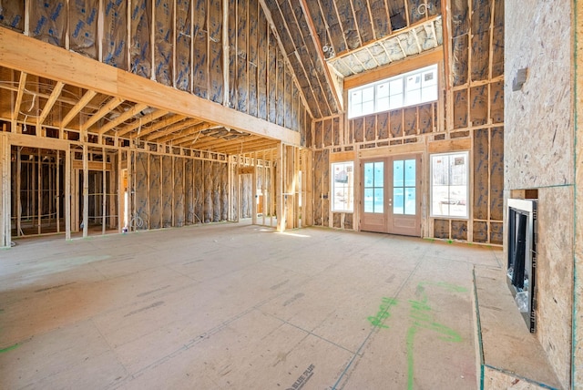 misc room featuring french doors, a towering ceiling, and a fireplace