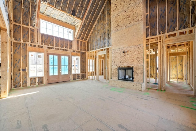 miscellaneous room with french doors, a large fireplace, and a towering ceiling