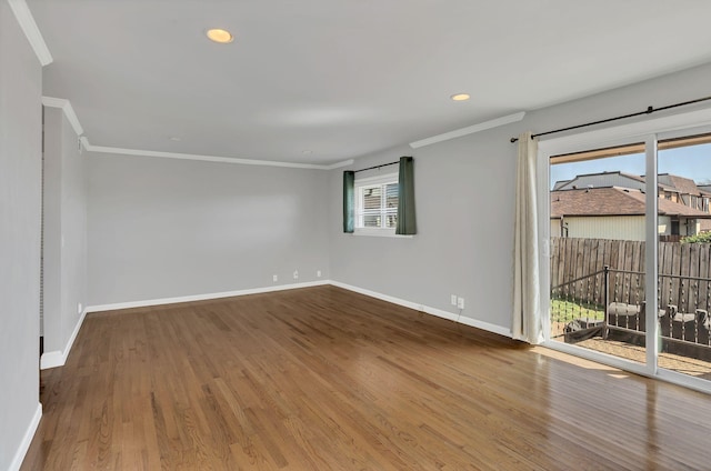 spare room with wood finished floors, baseboards, and ornamental molding