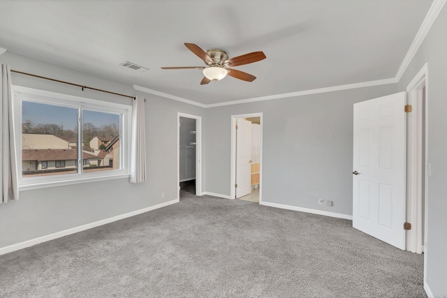 unfurnished bedroom with a spacious closet, visible vents, crown molding, and carpet