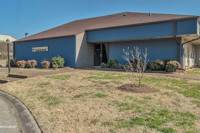 view of front of property featuring a front yard and roof with shingles