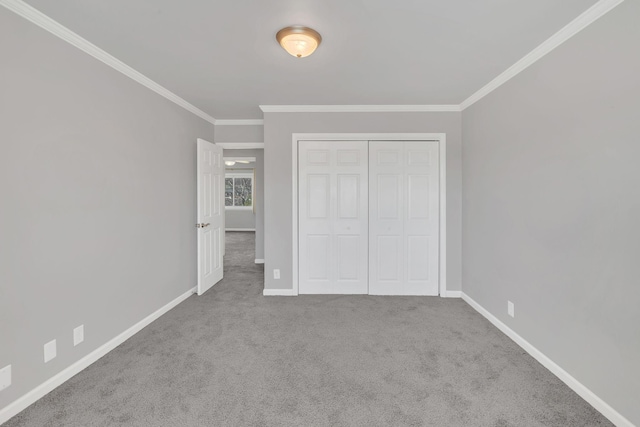 unfurnished bedroom featuring a closet, ornamental molding, baseboards, and carpet floors