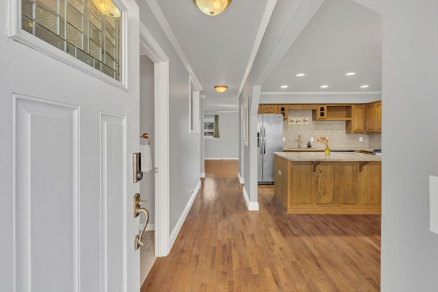 interior space with brown cabinetry, ornamental molding, a breakfast bar area, and stainless steel fridge with ice dispenser