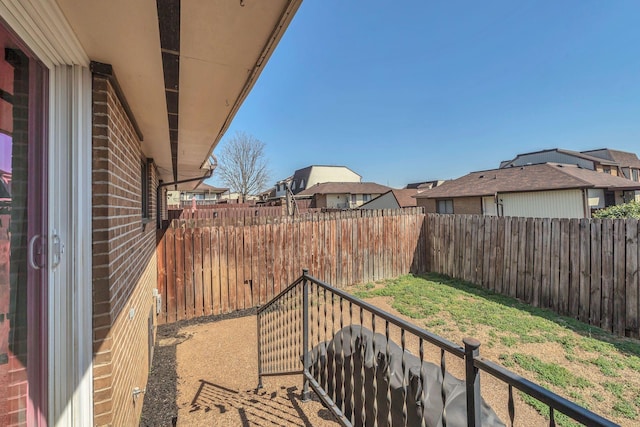 view of yard featuring a fenced backyard, a residential view, and a balcony