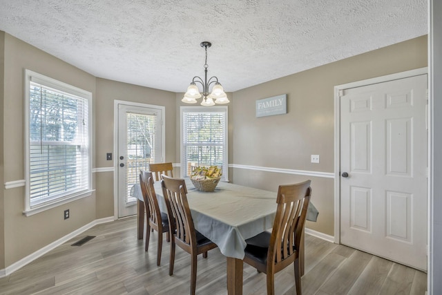 dining space with visible vents, an inviting chandelier, baseboards, and light wood-style floors