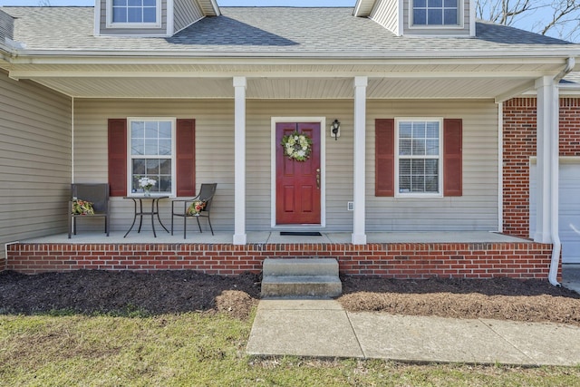 doorway to property with roof with shingles and a porch