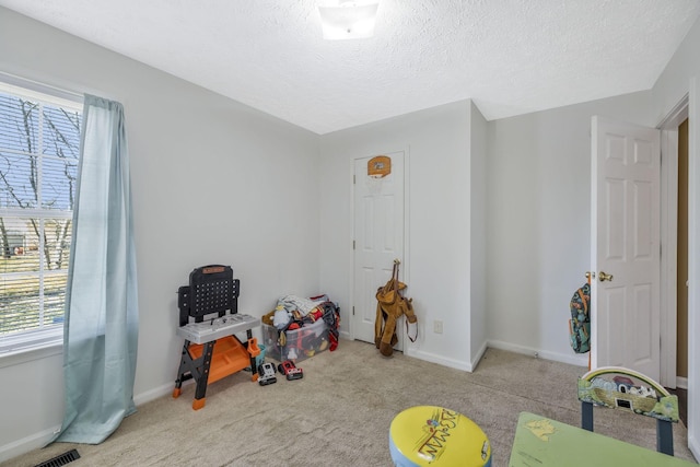 recreation room with baseboards, carpet flooring, a textured ceiling, and visible vents