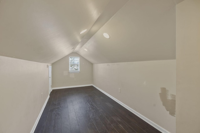 bonus room with dark wood finished floors, baseboards, and lofted ceiling