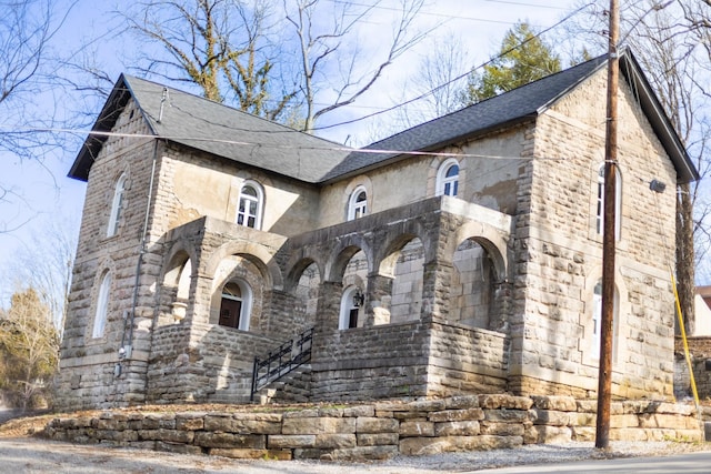 french country home featuring stone siding and a shingled roof