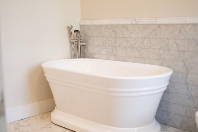 bathroom featuring tile walls and a freestanding tub