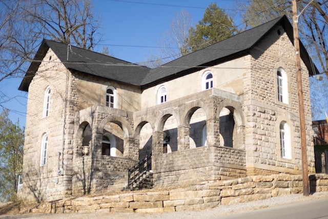 view of home's exterior featuring stone siding and roof with shingles