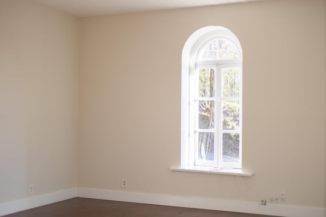 unfurnished room with baseboards and dark wood-style flooring