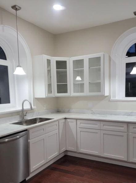 kitchen featuring dark wood finished floors, a sink, hanging light fixtures, light countertops, and dishwasher