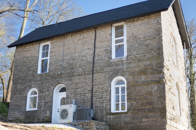 view of home's exterior with ac unit, central AC unit, and roof with shingles