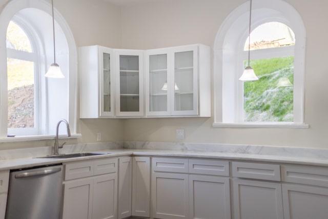 kitchen featuring a sink, hanging light fixtures, light countertops, glass insert cabinets, and dishwasher