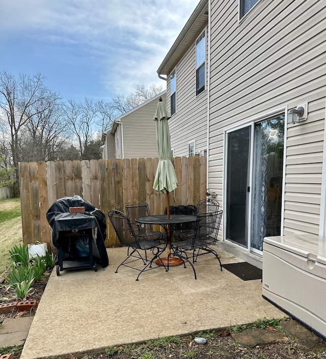 view of patio featuring outdoor dining space, a grill, and fence