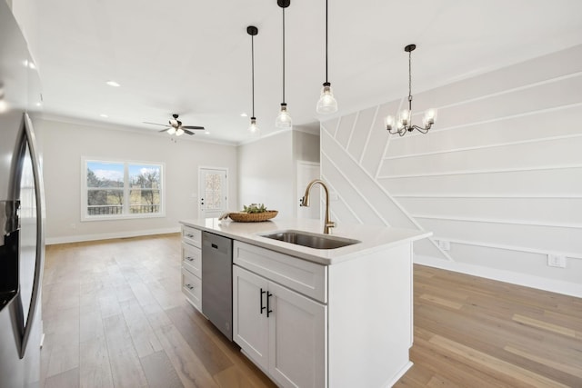 kitchen with stainless steel appliances, hanging light fixtures, a sink, light wood-style floors, and open floor plan