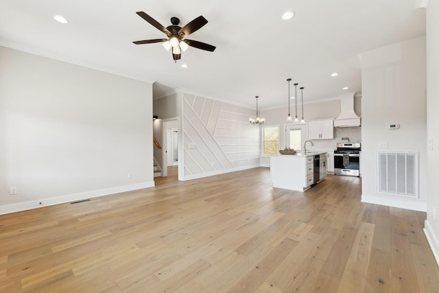 unfurnished living room featuring light wood-type flooring, visible vents, recessed lighting, stairway, and crown molding