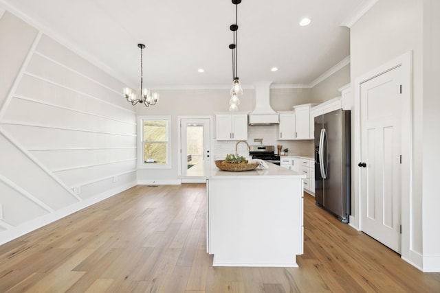 kitchen with light wood-type flooring, ornamental molding, custom range hood, appliances with stainless steel finishes, and light countertops