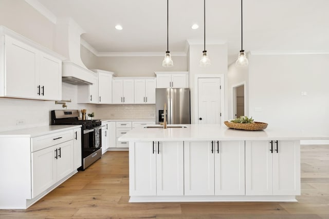 kitchen featuring backsplash, crown molding, stainless steel appliances, white cabinetry, and a kitchen island with sink