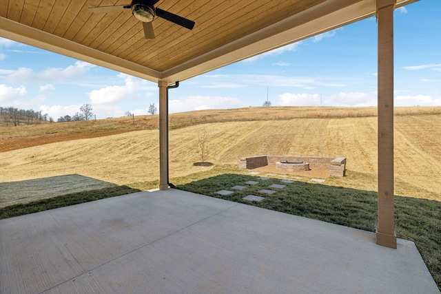 view of patio / terrace with a fire pit, ceiling fan, and a rural view