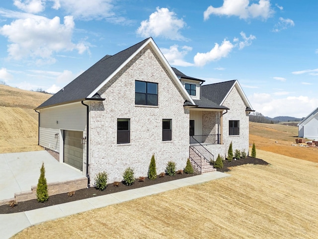 view of front of home with a front lawn, a garage, brick siding, and driveway