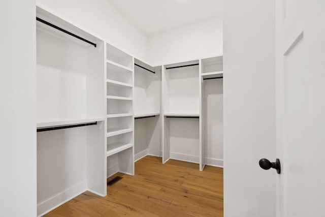 walk in closet featuring a barn door, visible vents, and light wood finished floors