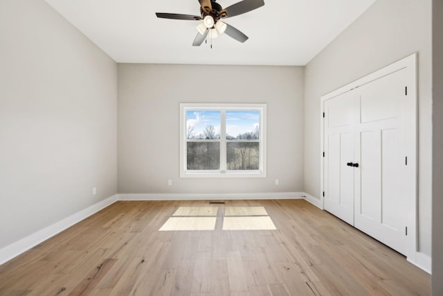 unfurnished bedroom featuring light wood-type flooring, baseboards, and a ceiling fan