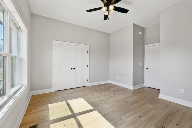 unfurnished bedroom with a closet, a ceiling fan, baseboards, and light wood finished floors