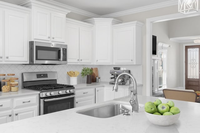 kitchen featuring a sink, stainless steel appliances, crown molding, and white cabinetry