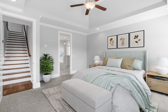 bedroom featuring baseboards, ensuite bath, a tray ceiling, ornamental molding, and carpet flooring