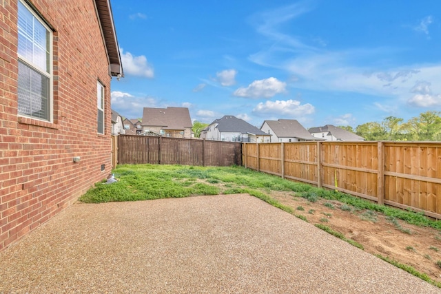 view of yard featuring a residential view, a patio, and a fenced backyard