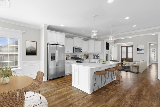 kitchen with dark wood-style floors, ornamental molding, a sink, light countertops, and appliances with stainless steel finishes