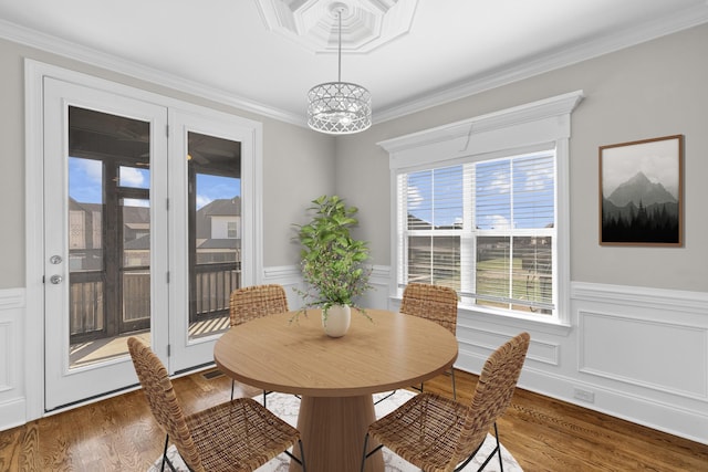 dining space featuring a wainscoted wall, wood finished floors, and crown molding