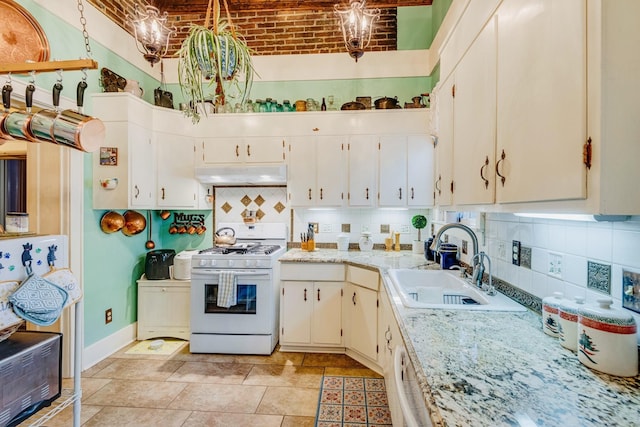 kitchen featuring under cabinet range hood, a sink, tasteful backsplash, brick ceiling, and white range with gas stovetop