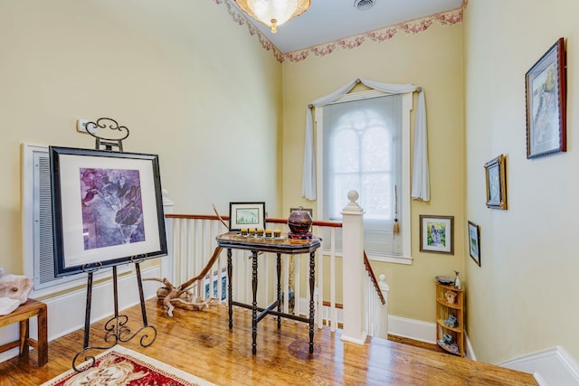 interior space featuring visible vents, an upstairs landing, baseboards, and wood finished floors