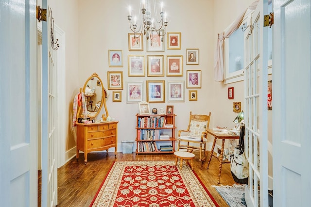 sitting room with wood finished floors, baseboards, and a chandelier