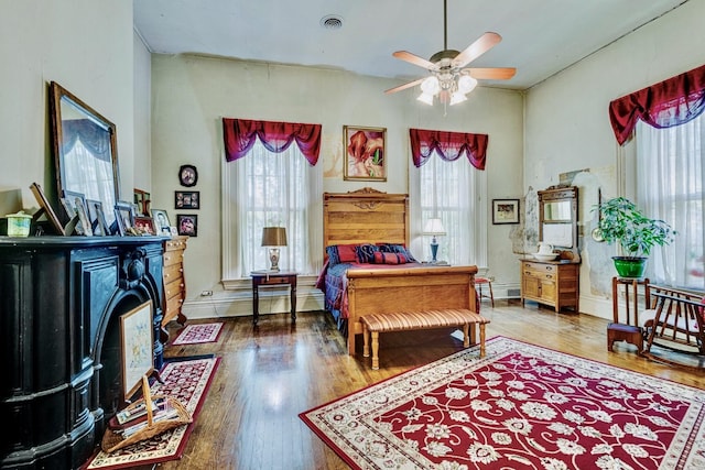 bedroom featuring multiple windows, wood finished floors, and a fireplace